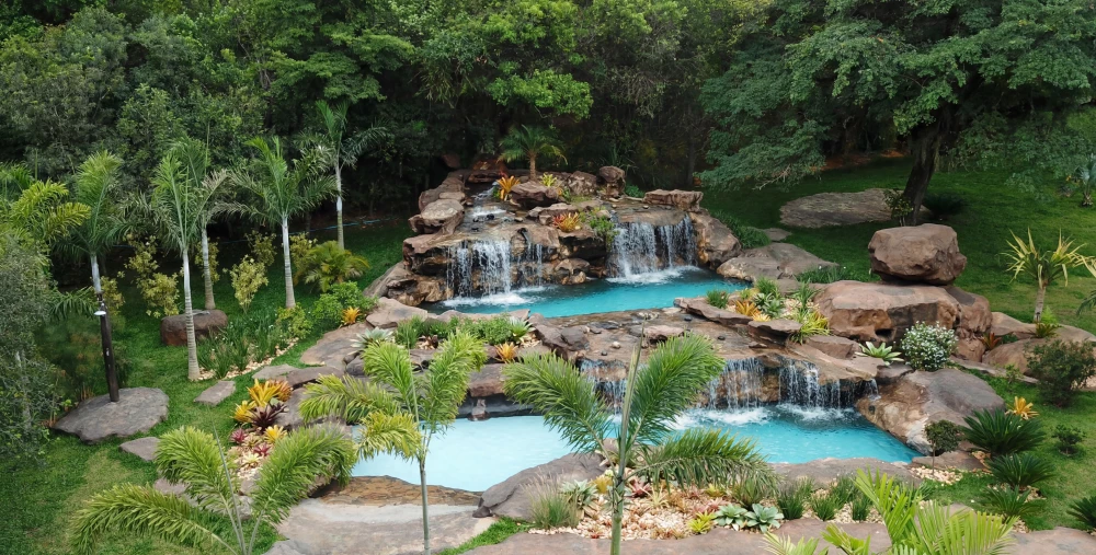 Vista aérea de piscina artificial com cascata cercada por palmeiras