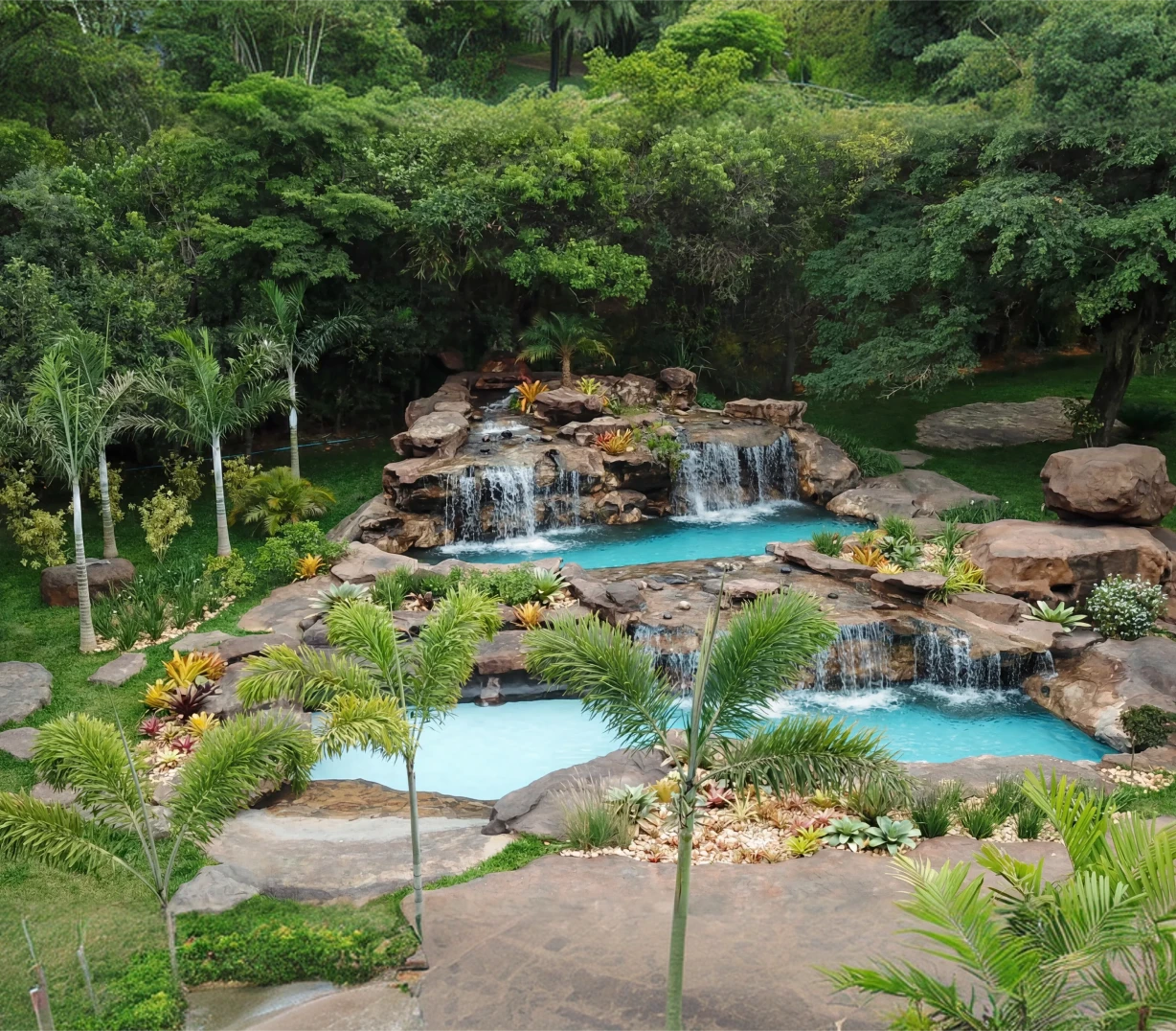 Cachoeira artificial em meio a pedras e vegetação tropical, com quedas d'água sobre piscinas artificiais