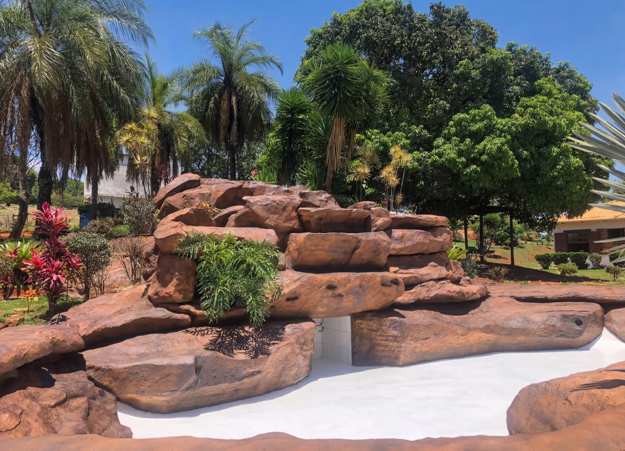 Cachoeira artificial de pedras em jardim com palmeiras